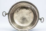 Prato com alças articuladas e flexíveis em prat... - Prato com alças articuladas e flexíveis em prata boliviana. Século XIX.
Apresenta borda circular, contornando aba guarnecida de friso com guilho...