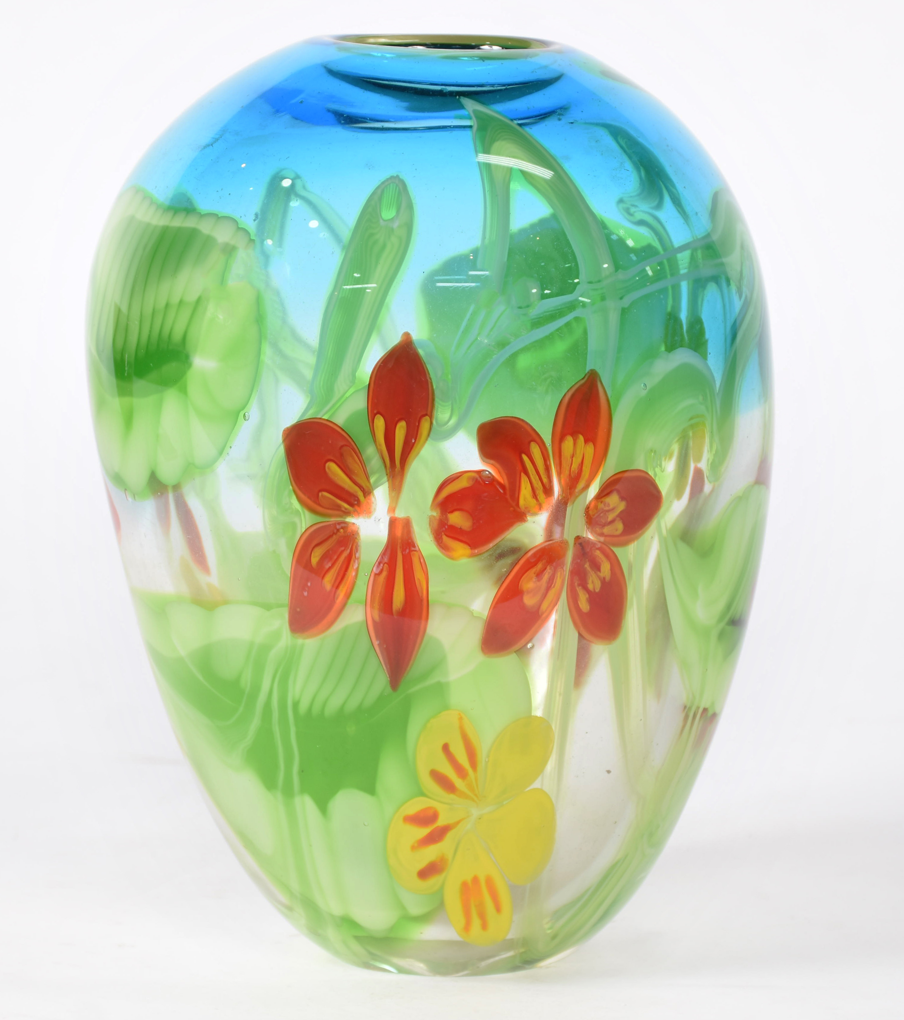 Jarra de vidro transparente em tons de verde e azul com flores em... - foto 1 de 3
