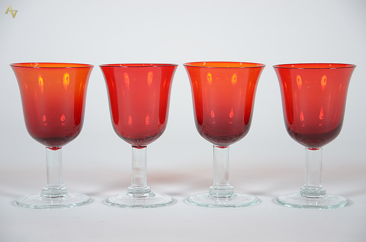 Quatro cálices de vidro vermelho.