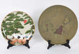 Dois pratos sendo um de porcelana com aves e ár... - Dois pratos sendo um de porcelana com aves e árvores em policromia e outro de bronze oriental com pássaros e figura em relevo.