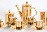 Pequeno serviço de café de porcelana dourada co... - Pequeno serviço de café de porcelana dourada composto de 6 xícaras com pires, bule, leiteira e açucareiro.