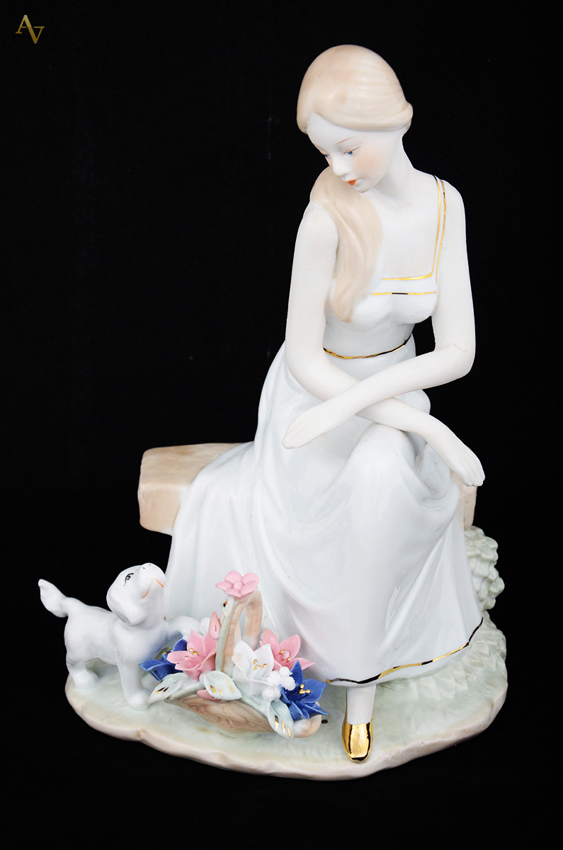Escultura de porcelana representando figura feminina com cão. Altura...