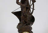 Escultura em petit bronze com relógio &#34;Stee... - Escultura em petit bronze com relógio &#34;Steering for home&#34; - Altura total 71 cm.