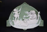 Placa de porcelana Wedgwood na cor verde decora... - Placa de porcelana Wedgwood na cor verde decorada com cena romântica em relevo branco. Medidas 20 x 25 cm.
