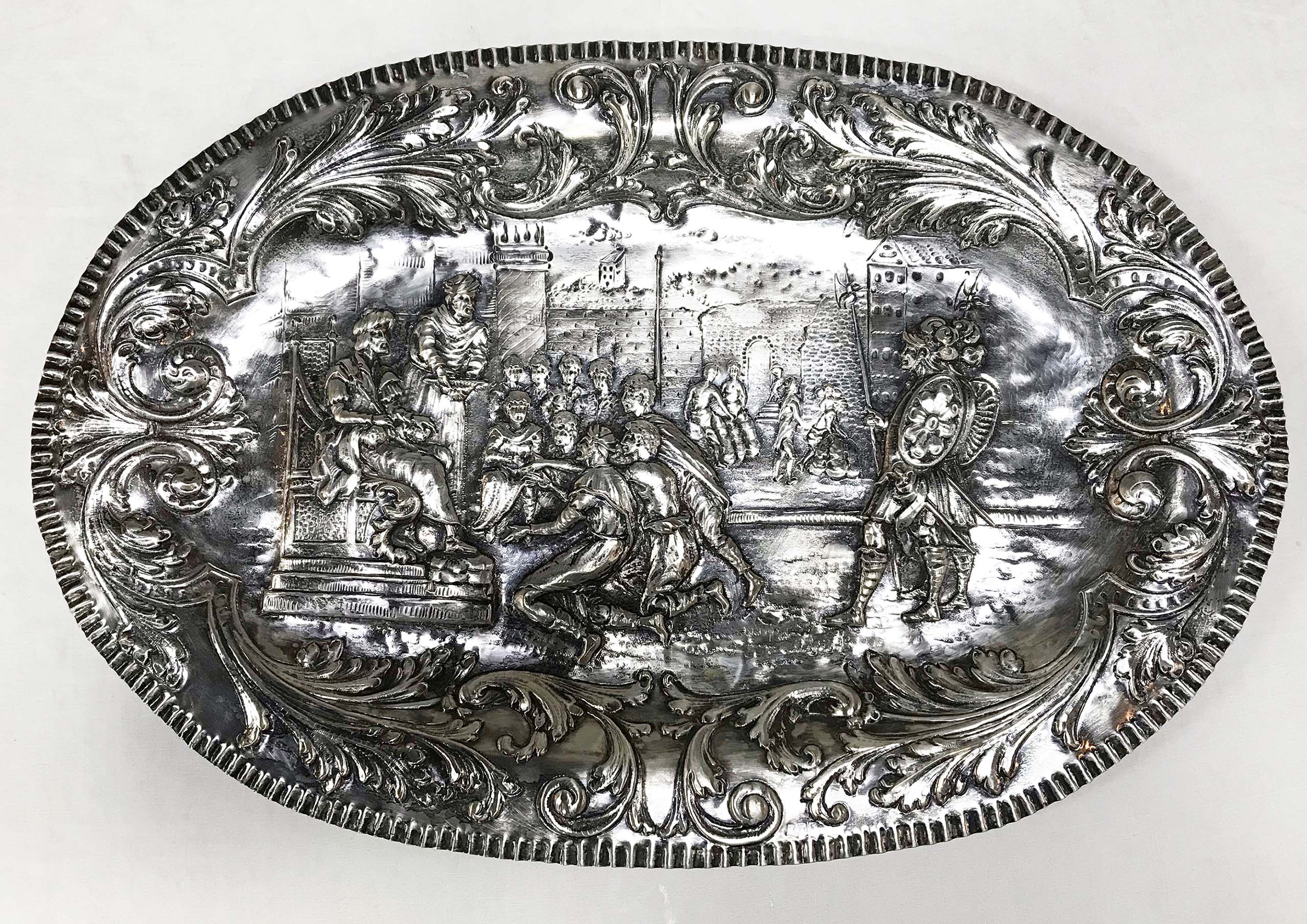 Medalhão oval de prata contrastada, com cenas de guerreiros em relevo. - foto 1 de 3