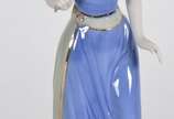 Estatueta de porcelana policromada representand... - Estatueta de porcelana policromada representando figura feminina com flor.