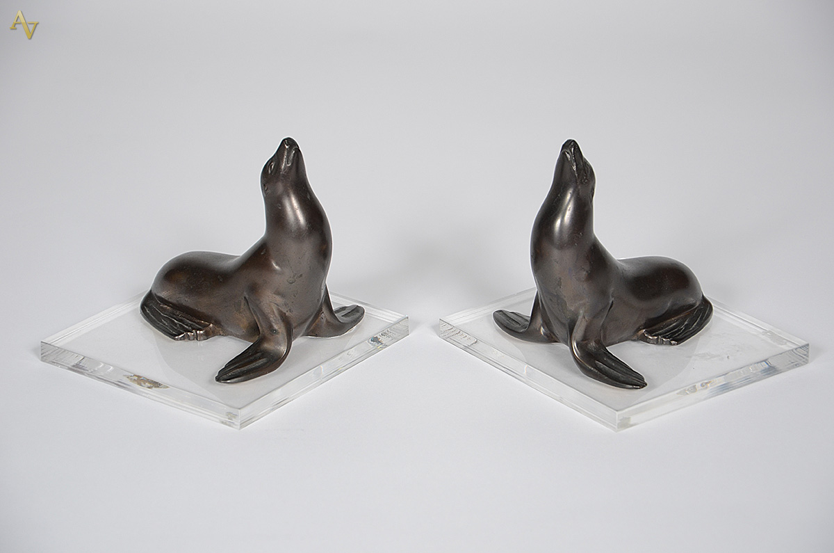 Par de serre-livres de bronze representando focas, bases de acrílico...