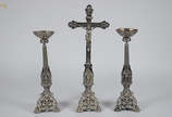 Três peças de metal prateado, sendo um crucifix... - Três peças de metal prateado, sendo um crucifixo e par de castiçais. Crucifixo 64 cm e castiçais 49,5 cm.