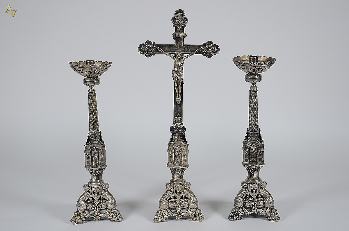 Três peças de metal prateado, sendo um crucifixo e par de castiçais...