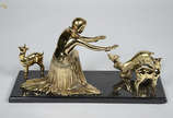 Grupo escultórico de metal dourado representand... - Grupo escultórico de metal dourado representando figura feminina com carneiros, base de mármore. Medidas 47 x 18 altura 24 cm.