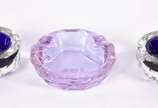 Três cinzeiros de bloco de cristal sendo 1 lilá... - Três cinzeiros de bloco de cristal sendo 1 lilás e 2 com detalhes azuis.