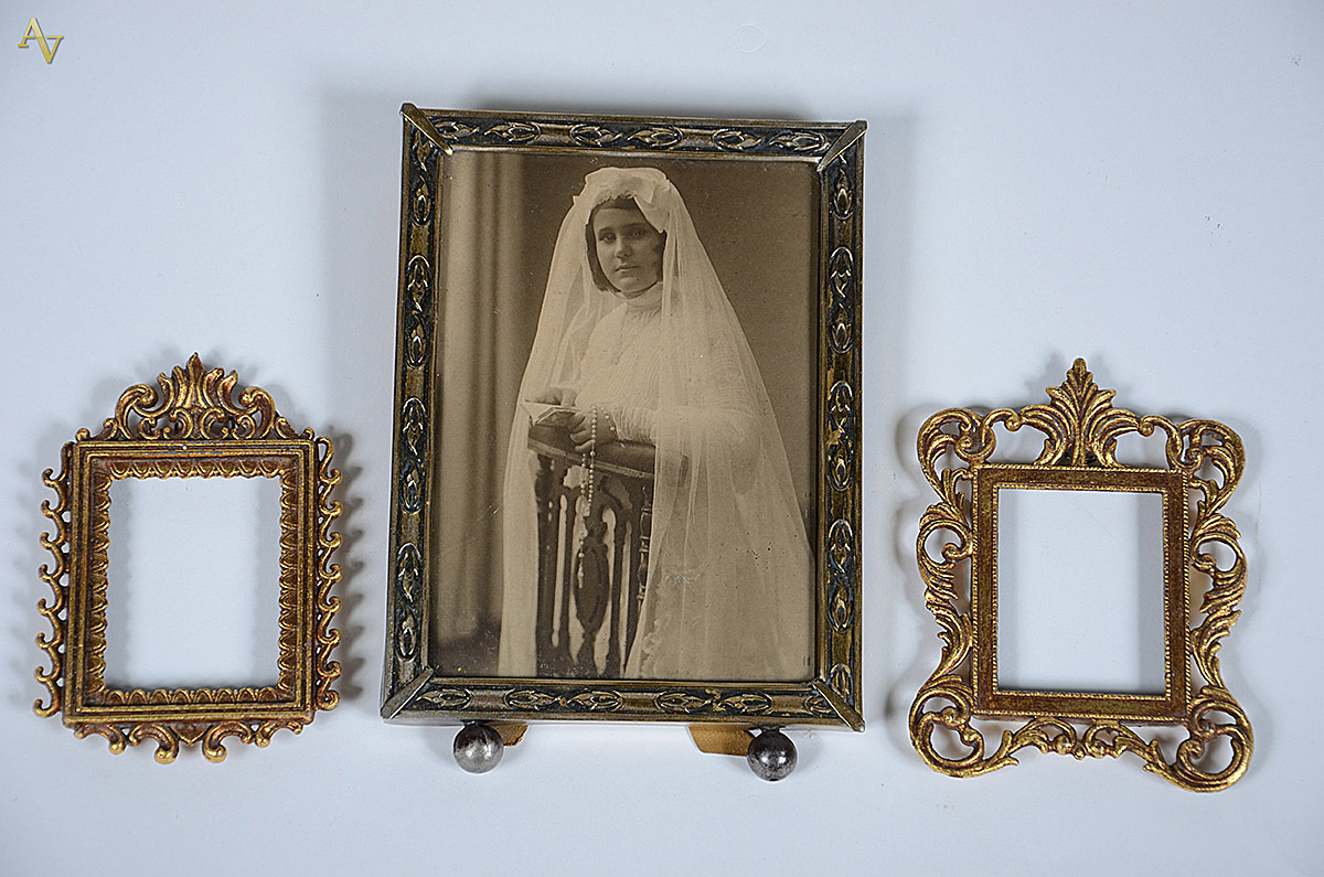 Conjunto com três porta-retratos metal dourado, um com moldura com...