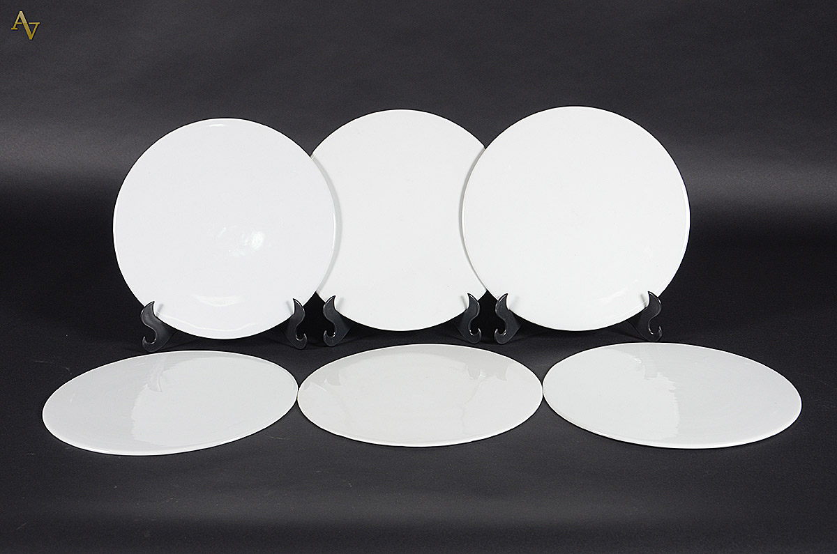 Conjunto com seis sousplats de porcelana branca, diâmetro 32 cm cada.