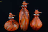 Três garrafas de murano cor de abóbora com pó d... - Três garrafas de murano cor de abóbora com pó de ouro - Tampas com formato de pato - Alturas 21 cm, 24 cm e 35 cm (uma tampa lascada)