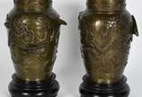Par de vasos de bronze oriental com aves e folh... - Par de vasos de bronze oriental com aves e folhagens em relevo, bases de madeira.