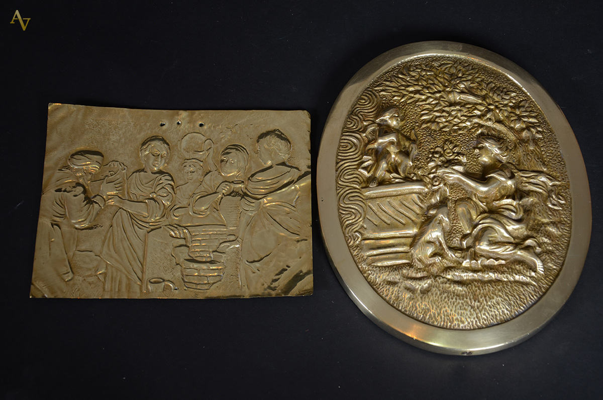 Duas placas, sendo uma de bronze feitio oval com figura de mulher...