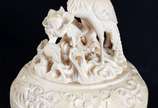 Duas estatuetas de marfim, sendo um vaso trabal... - Duas estatuetas de marfim, sendo um vaso trabalhado com figuras e aves em relevo (pequena parte faltando na borda) e, grupo escultórico represen...