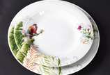Aparelho de jantar de porcelana branca com flor... - Aparelho de jantar de porcelana branca com flores e pássaros em policromia com monograma no fundo composto de: 12 pratos rasos, 12 fundos, 12 de...