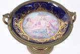 Fruteira de porcelana francesa de Sèvres e apli... - Fruteira de porcelana francesa de Sèvres e aplicações de bronze com cenas de ninfas em policromia, borda azul cobalto com guirlandas douradas, a...