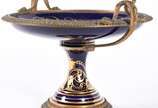 Fruteira de porcelana francesa de Sèvres e apli... - Fruteira de porcelana francesa de Sèvres e aplicações de bronze com cenas de ninfas em policromia, borda azul cobalto com guirlandas douradas, a...
