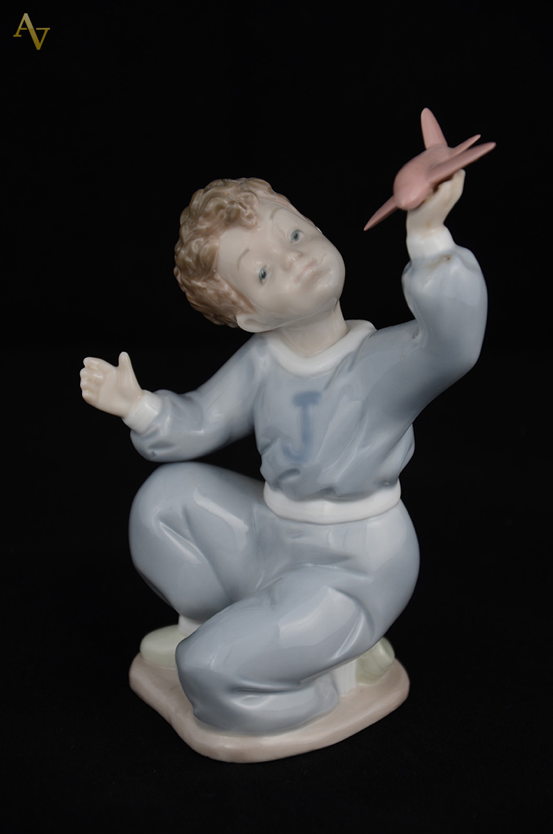 NAO - Escultura em porcelana representando menino c/ avião. Altura... - foto 1 de 2