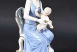 Grupo escultórico de porcelana representando mã... - Grupo escultórico de porcelana representando mãe com bebê.
