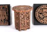 Três peças orientais de madeira entalhada, send... - Três peças orientais de madeira entalhada, sendo mesa indiana com suporte e dois quadros representando mandala e elefantes.