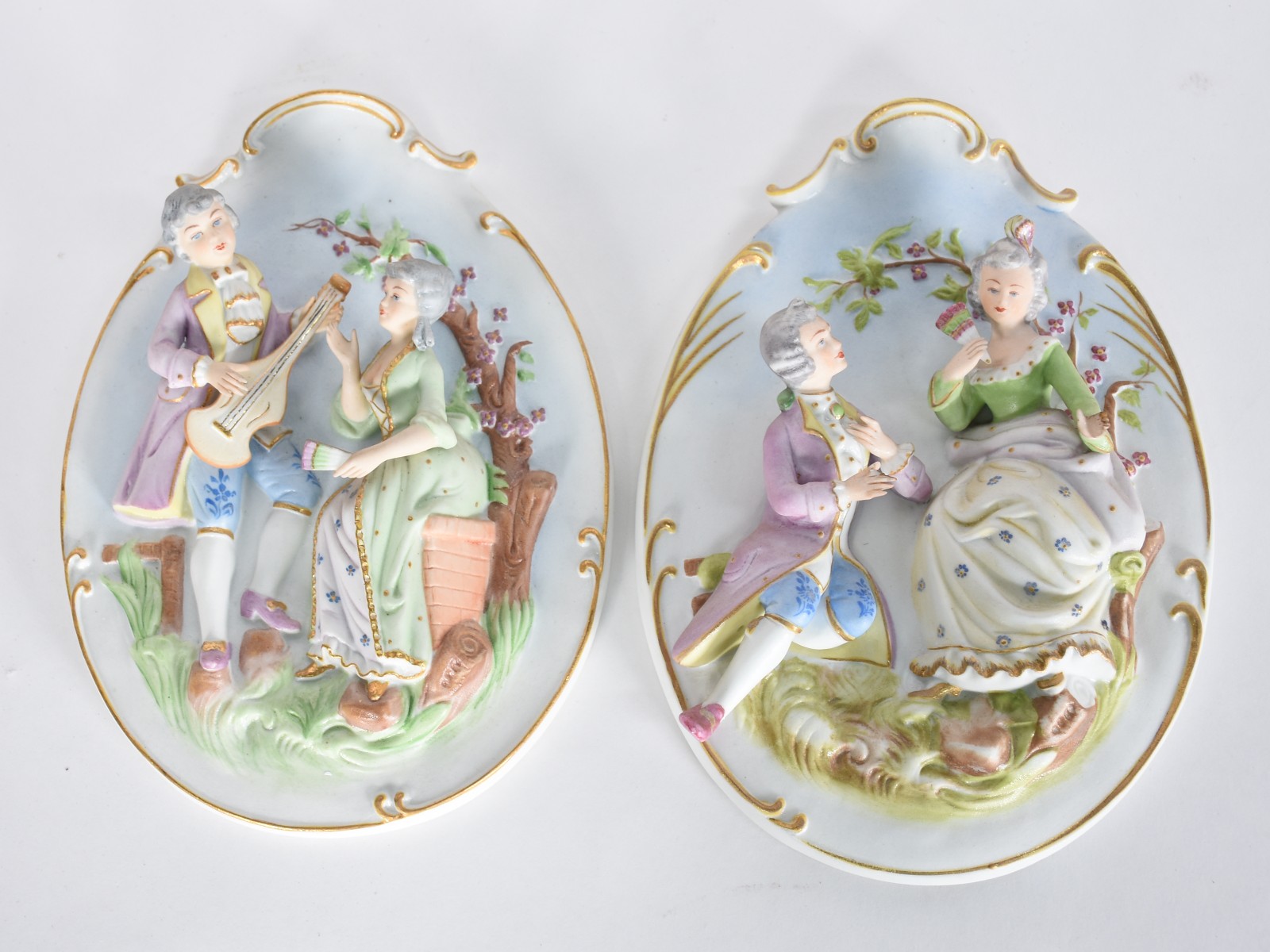 Par de placas de porcelana policromada com cenas românticas em relevo... - foto 1 de 4