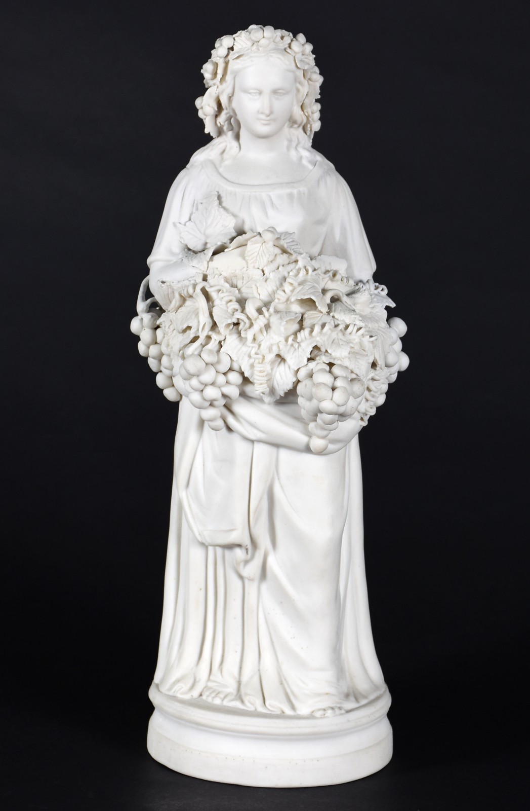 Escultura de biscuit representando dama com cachos de uvas nas mãos. - foto 1 de 4