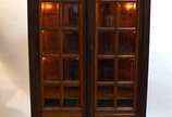 Vitrine de madeira nobre com duas portas de vid... - Vitrine de madeira nobre com duas portas de vidro bisotado, prateleiras de madeira e iluminação interna.