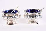 Par de saleiros de prata inglesa contrastada co... - Par de saleiros de prata inglesa contrastada com colheres, recipientes internos de vidro azul. Peso da prata: 90 g  (Por motivos de segurança a ...