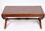 Mesa de centro de madeira nobre com tampo de co... - Mesa de centro de madeira nobre com tampo de couro, abas laterais, uma gaveta e ponteiras em garra de bronze.