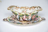 Molheira de porcelana italiana Capodimonte com ... - Molheira de porcelana italiana Capodimonte com figuras em relevo policromado. Medidas 15,5 x 27 cm altura 10 cm.
