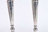 Par de castiçais de prata contraste 833 mls., b... - Par de castiçais de prata contraste 833 mls., bases com guirlandas florais em relevo e colunas com folhagens cinzeladas.  Um deles ligeiramente ...