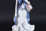 Estatueta de porcelana policromada representand... - Estatueta de porcelana policromada representando dama com cachorro e cesta de flores.