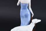 Estatueta de porcelana policromada representand... - Estatueta de porcelana policromada representando dama com cachorro e flor.