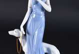 Estatueta de porcelana policromada representand... - Estatueta de porcelana policromada representando dama com cachorro e flor.