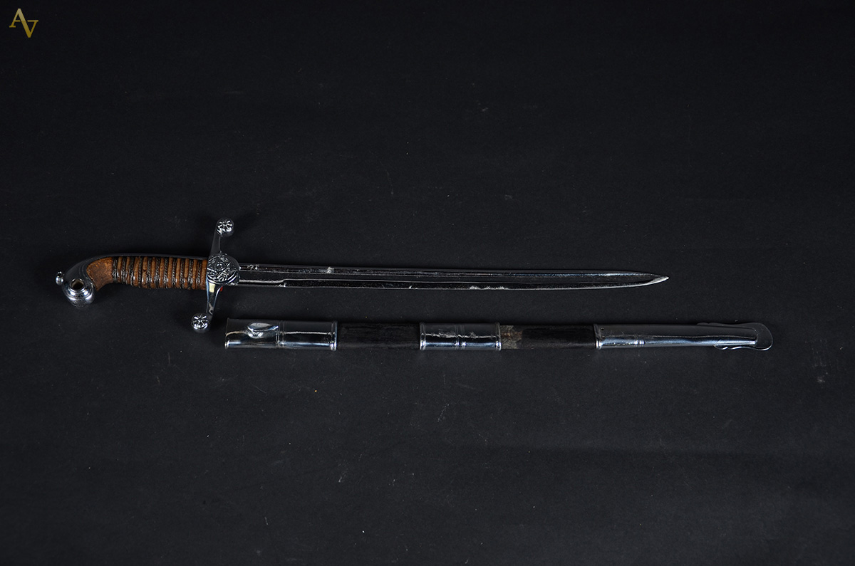 Pequena espada com bainha de metal. Medida: 57 cm