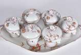 Seis cremeiras e presentoir de porcelana france... - Seis cremeiras e presentoir de porcelana francesa com flores em policromia, laterais na forma de caras de cachorros, marcados Jacob Petit na bas...