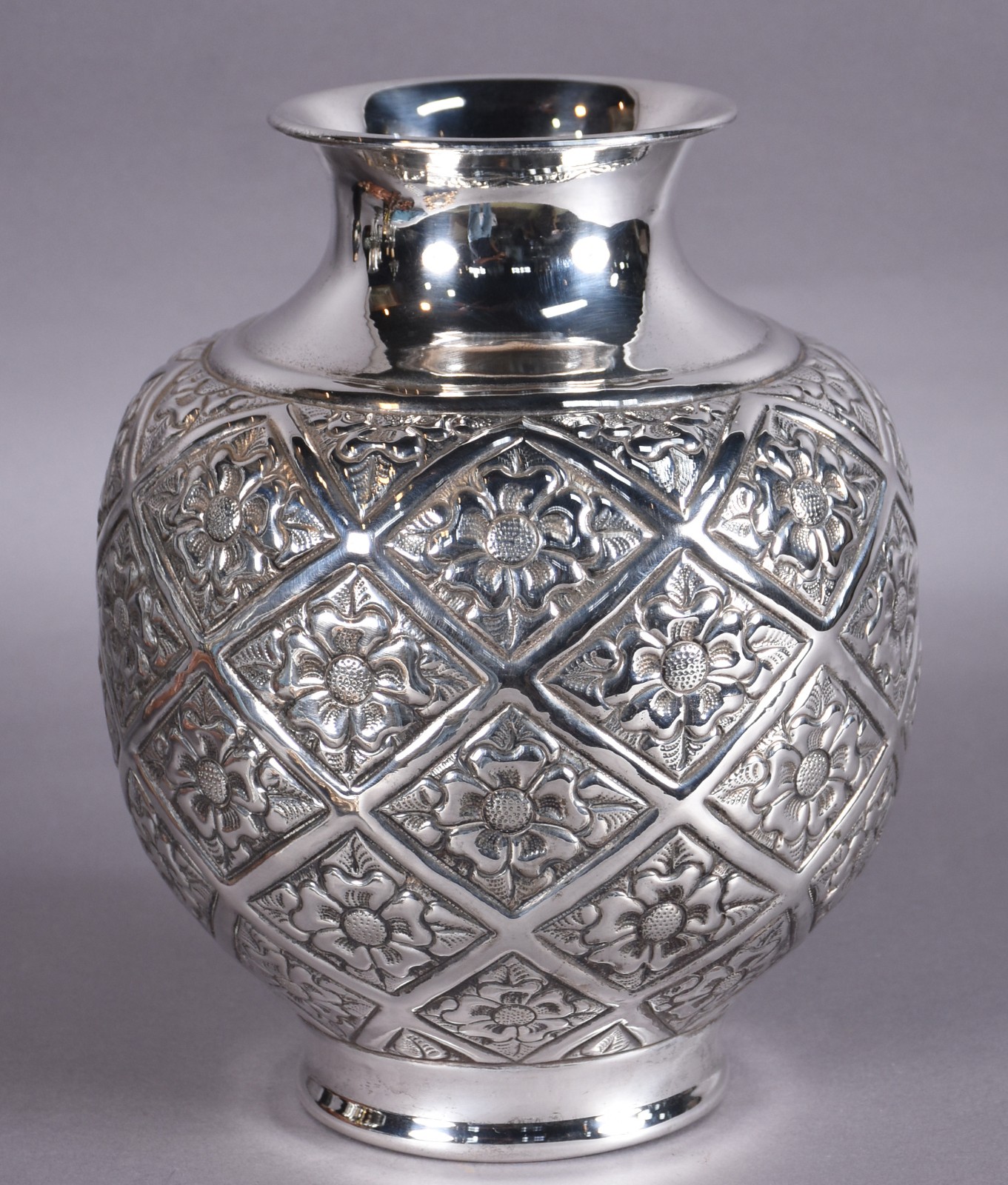 Vaso decorativo de metal prateado com flores em relevo, feitio bojudo. - foto 1 de 2