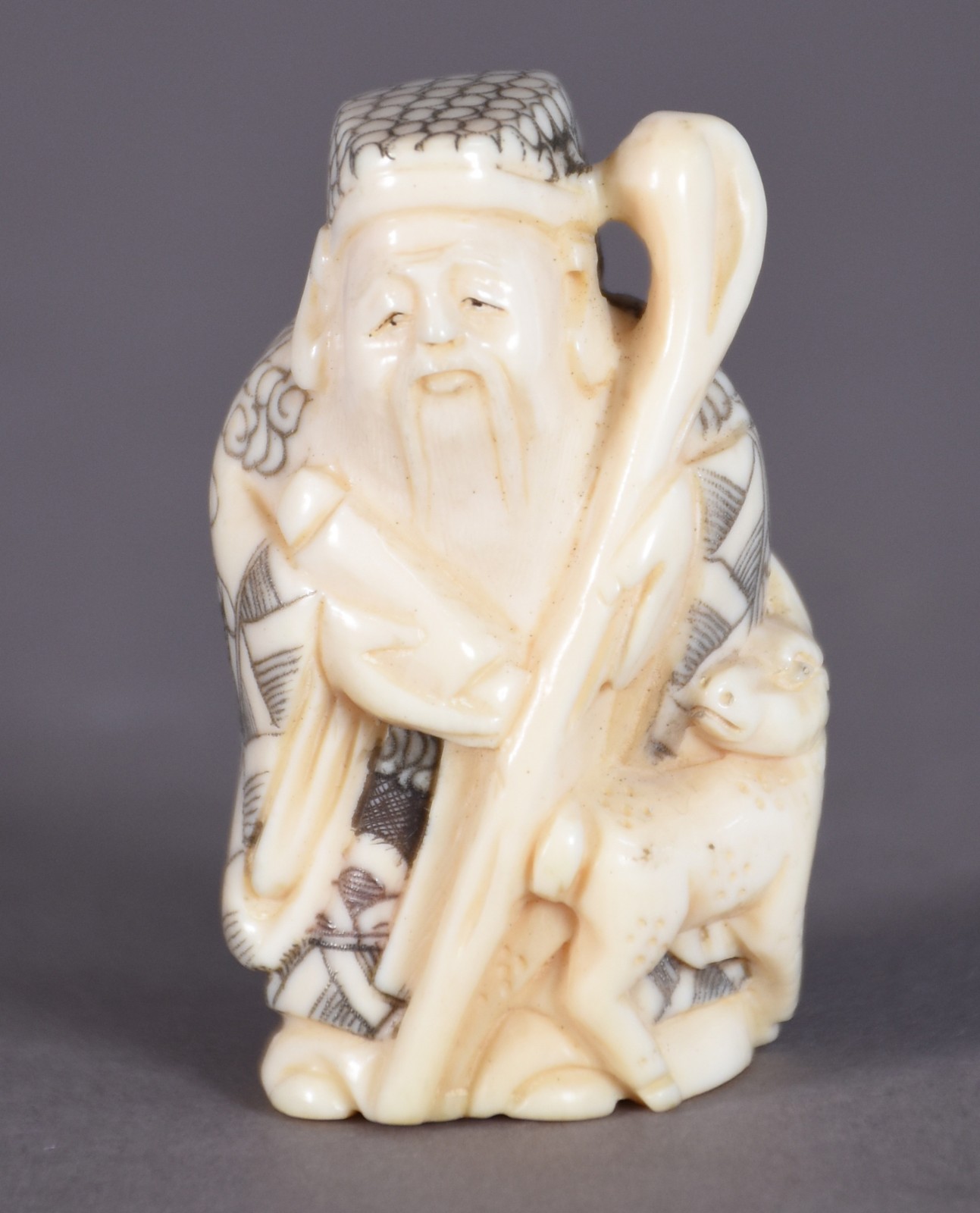 Netsuke de marfim representando sábio com cajado e animal, assinado. - foto 1 de 3