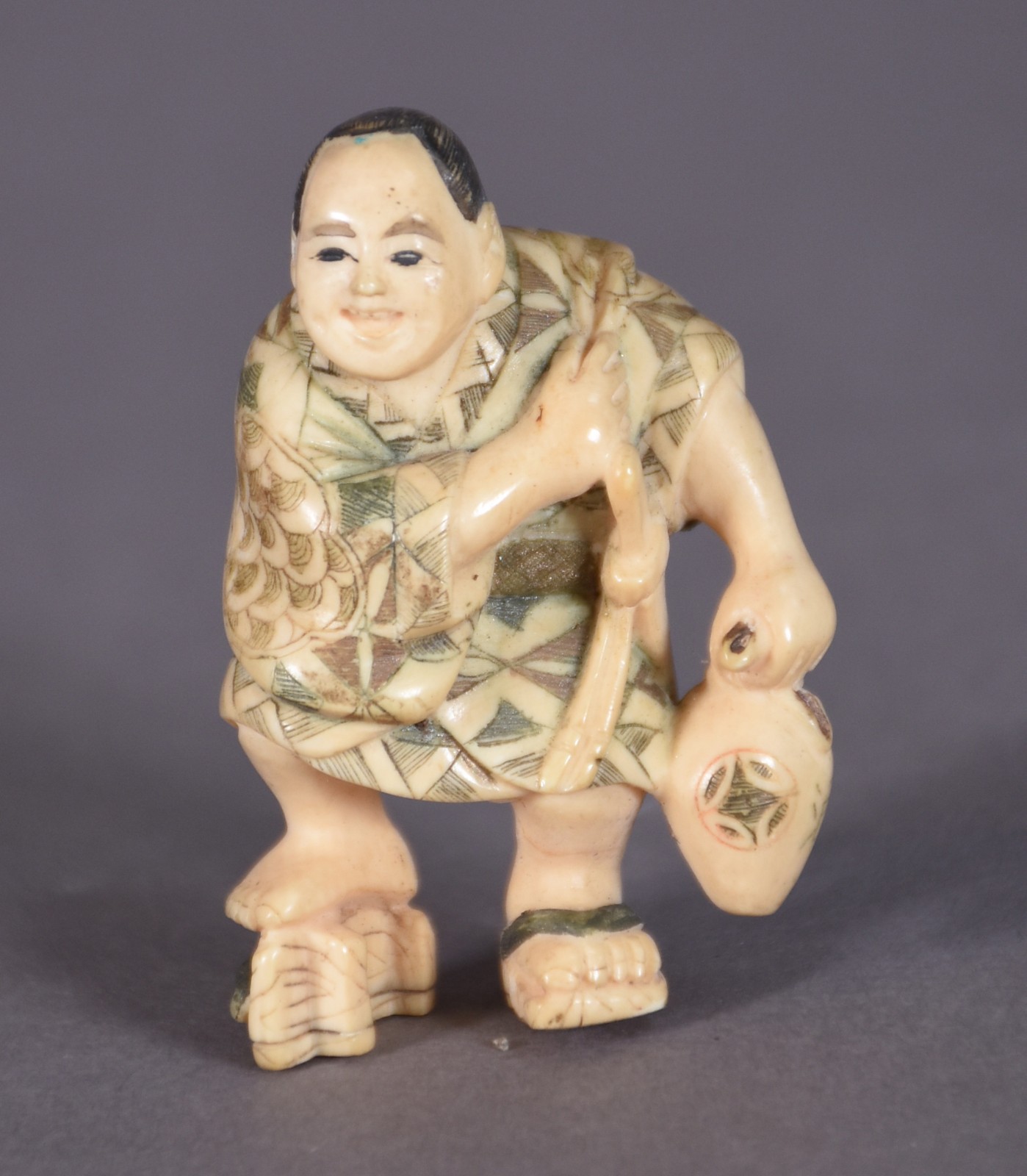 Netsuke de marfim policromado representando figura com cantil. - foto 1 de 3