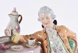Grupo escultórico de porcelana tcheca Royal Dux... - Grupo escultórico de porcelana tcheca Royal Dux policromada com realces dourados representando casal tomando chá. Alça do bule colada e pequenos...