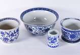 Quatro peças de porcelana oriental azul e branc... - Quatro peças de porcelana oriental azul e branca, sendo: bowl, cachepot (bicado na borda) com presentoir; cachepot e vaso cilíndrico.