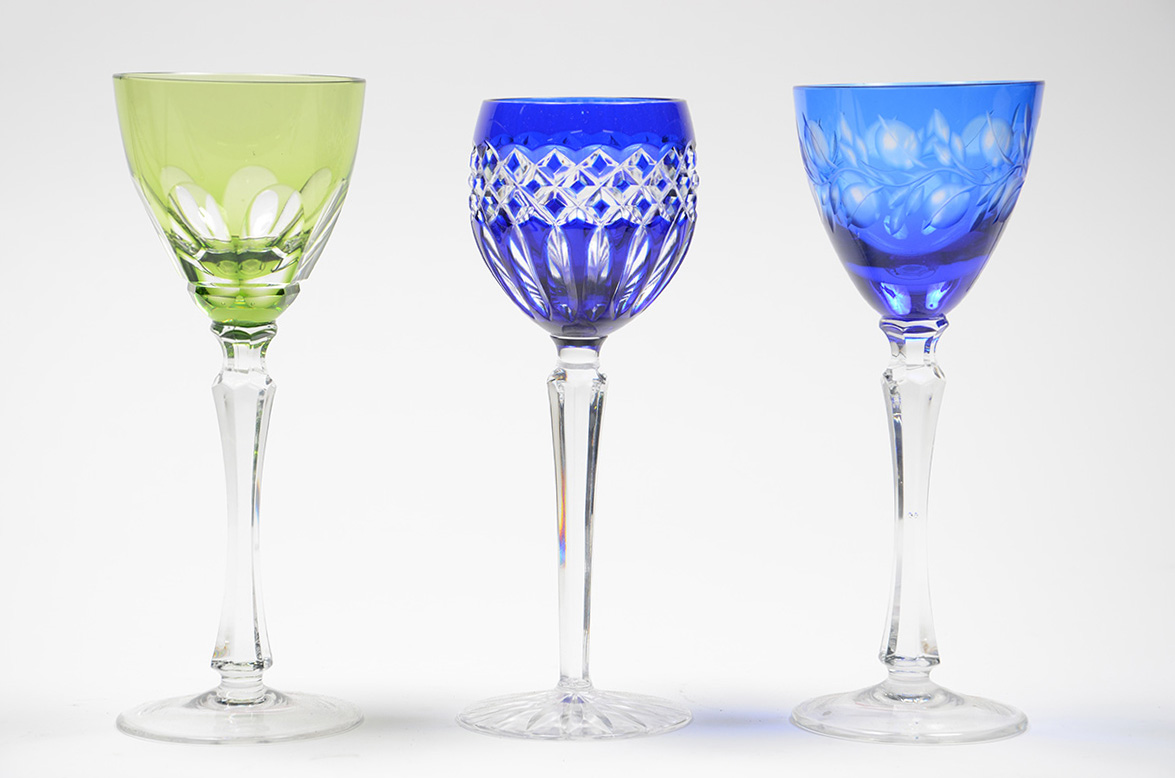 Três cálices de cristal de pé alto, diversas cores e lapidações.