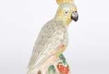 Escultura de porcelana representando cacatua em... - Escultura de porcelana representando cacatua em policromia.