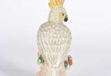 Escultura de porcelana representando cacatua em... - Escultura de porcelana representando cacatua em policromia.
