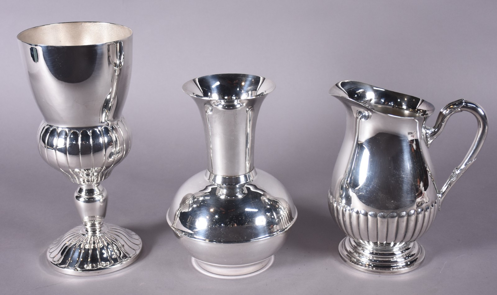 Três peças de metal prateado, sendo jarra para água e 2 vasos. - foto 1 de 6