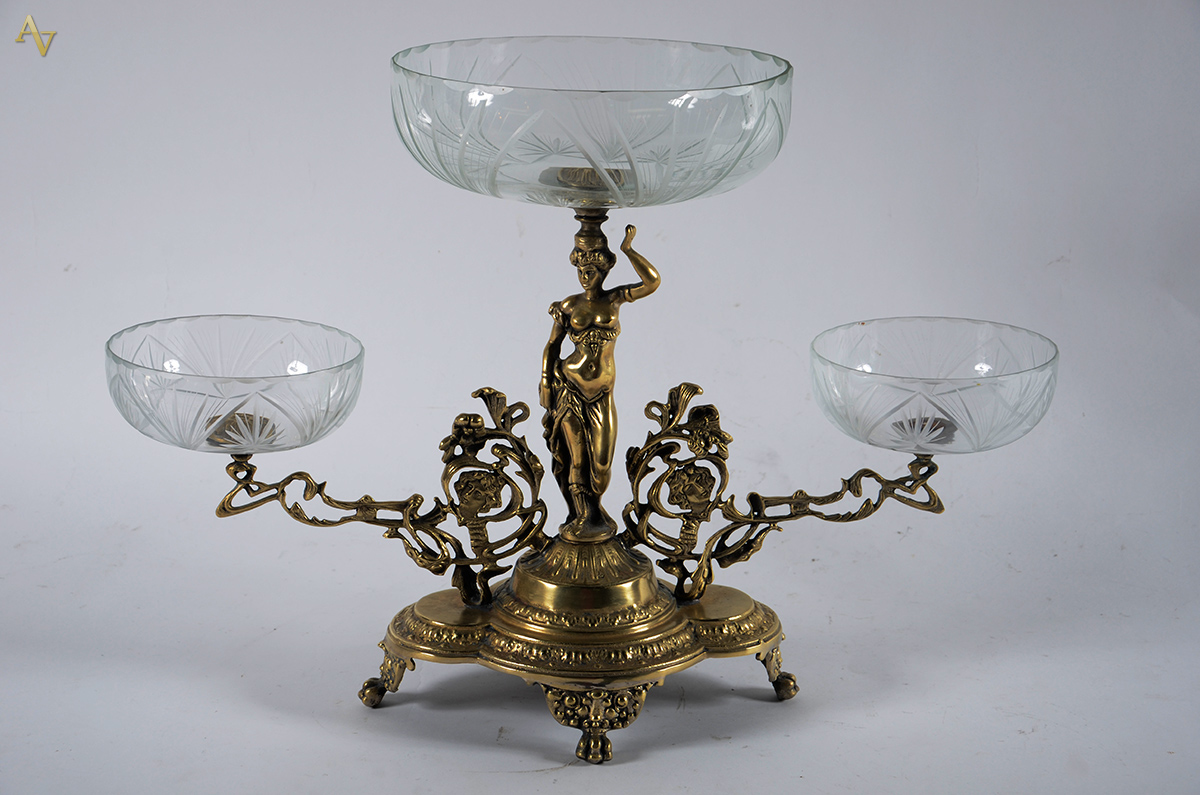 Fruteira de metal dourado, base com figura feminina e rostos no...