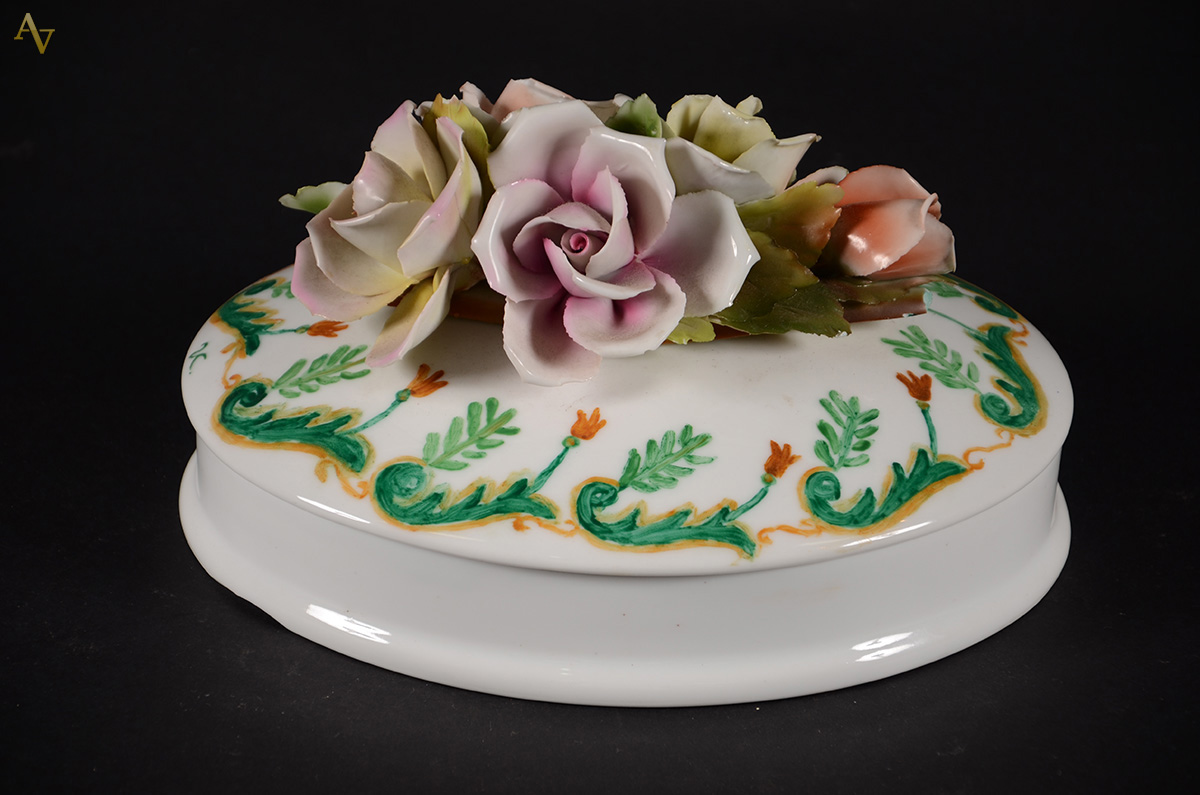 Caixa oval de porcelana com flores em relevo policromado na tampa...